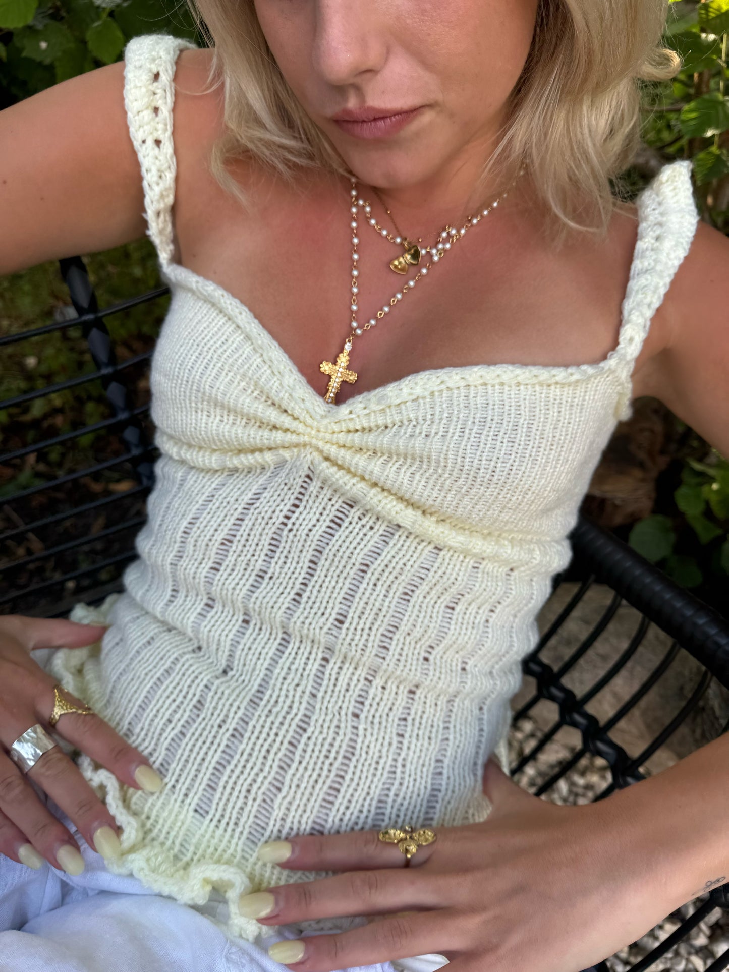 Woman wearing a white crochet top with a blurred background