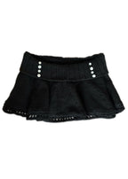 Black knit skirt with silver buttons on a white background
