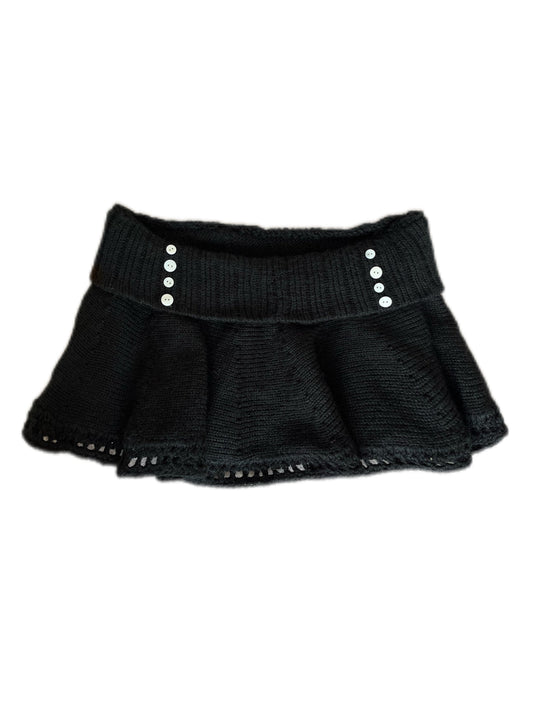 Black knit skirt with silver buttons on a white background
